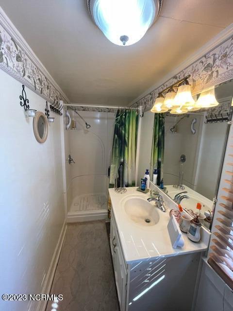 bathroom featuring vanity, baseboards, and walk in shower