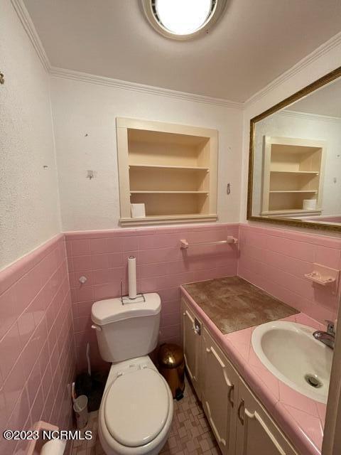 bathroom featuring built in features, crown molding, toilet, wainscoting, and vanity