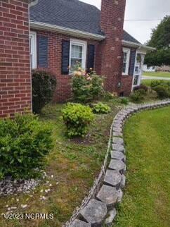 view of side of home featuring brick siding, a yard, and a chimney