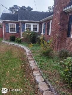 view of side of property featuring brick siding, a yard, and a chimney