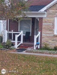 doorway to property with covered porch and brick siding