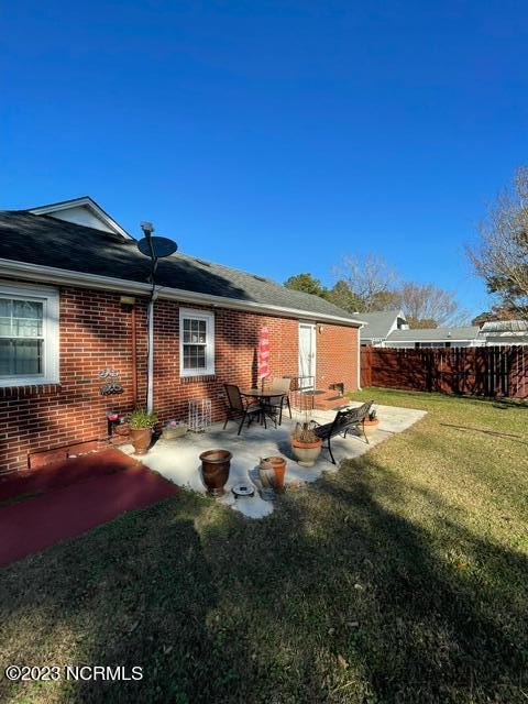 back of property featuring brick siding, a yard, a patio, and fence