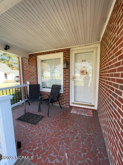 property entrance with covered porch and brick siding