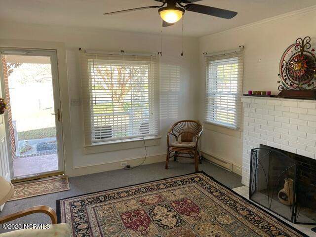 sitting room featuring a brick fireplace, baseboards, and a ceiling fan