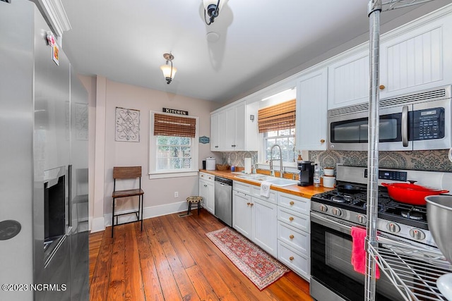 kitchen with wooden counters, appliances with stainless steel finishes, white cabinets, and sink