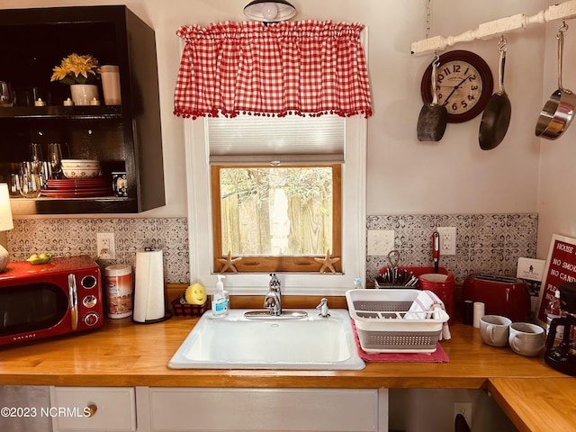 kitchen featuring wood counters, decorative backsplash, and sink