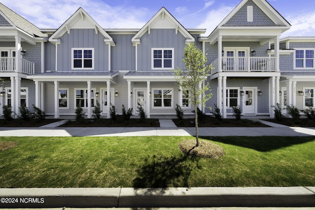 multi unit property with french doors, a front lawn, and a balcony