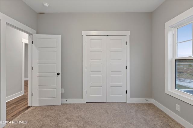 unfurnished bedroom featuring light carpet and a closet