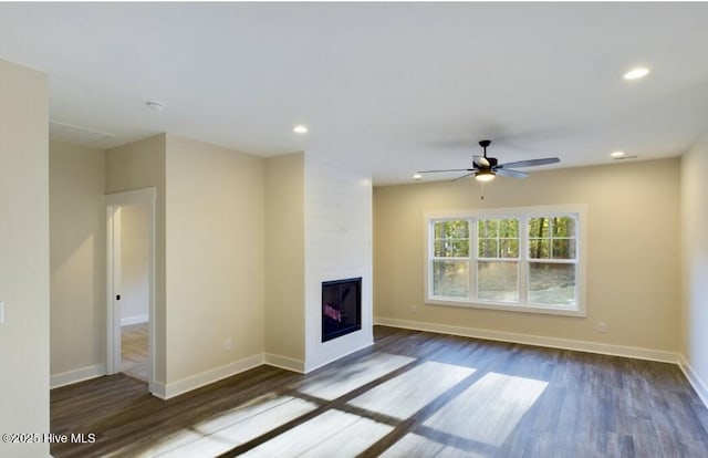 unfurnished living room featuring ceiling fan, recessed lighting, a large fireplace, wood finished floors, and baseboards