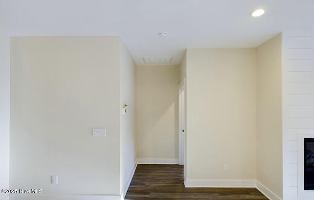 empty room with recessed lighting, a fireplace, dark wood finished floors, and baseboards