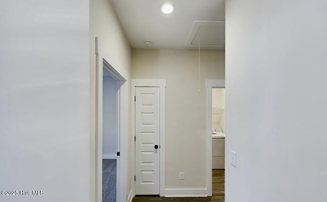 hallway with attic access, washer / clothes dryer, baseboards, and dark wood-style flooring