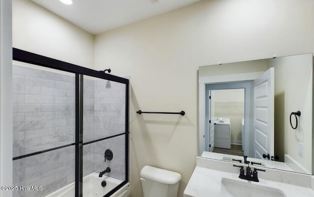 bathroom with washer / clothes dryer, shower / bath combination with glass door, vanity, and toilet