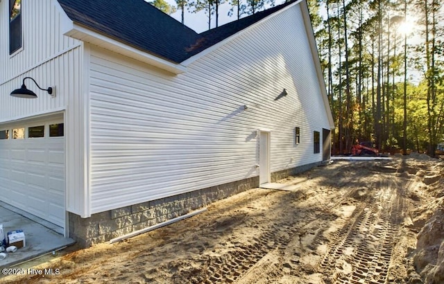 view of home's exterior featuring a garage and roof with shingles