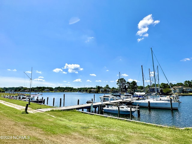 view of dock featuring a lawn and a water view