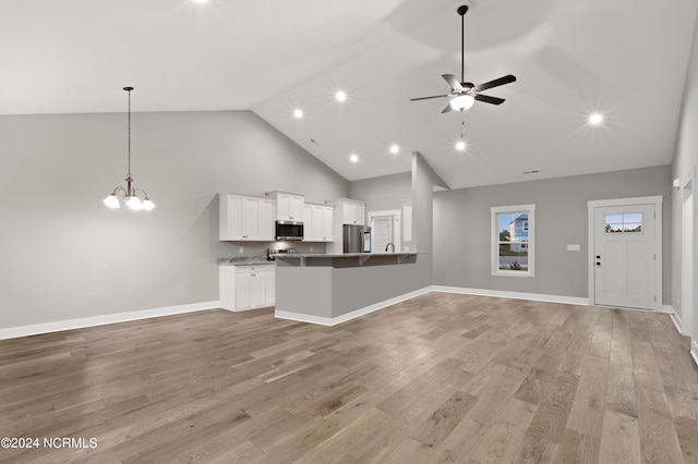 unfurnished living room with high vaulted ceiling, ceiling fan with notable chandelier, and light hardwood / wood-style flooring