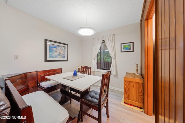 dining space with a textured ceiling and light wood-type flooring