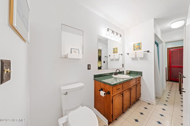 bathroom with tile floors, oversized vanity, and toilet