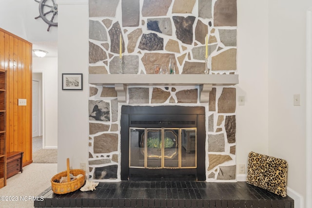 room details with a stone fireplace, wood walls, and carpet flooring