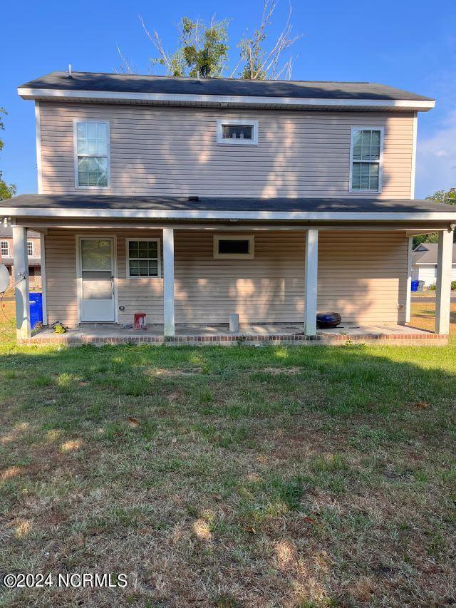 rear view of property featuring a lawn