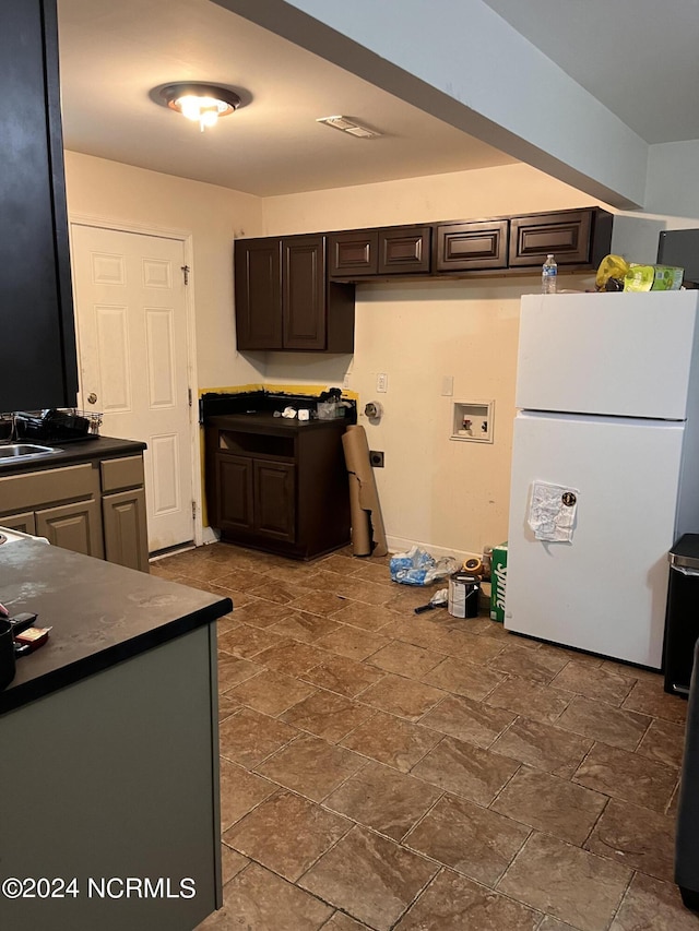 kitchen featuring dark brown cabinetry, sink, and white refrigerator