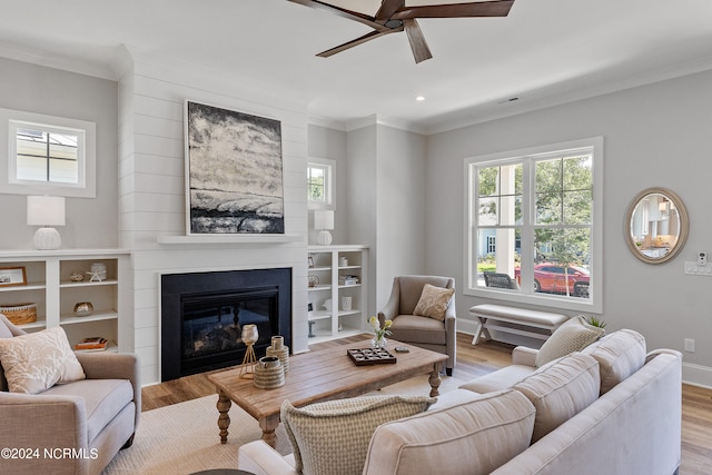 living room featuring ceiling fan, a wealth of natural light, a fireplace, and light hardwood / wood-style floors