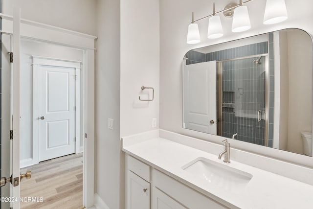 bathroom with a shower with shower door, hardwood / wood-style floors, toilet, and vanity