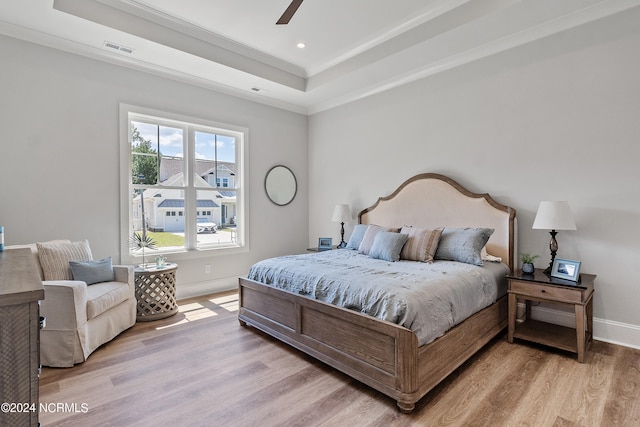 bedroom featuring a tray ceiling, light hardwood / wood-style flooring, and ceiling fan