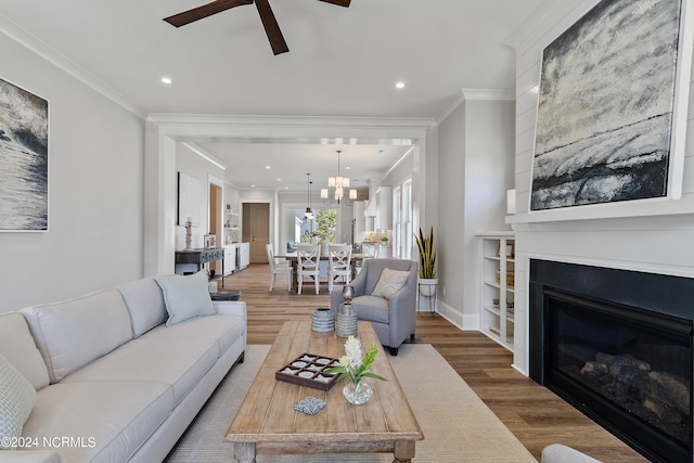 living room featuring crown molding, ceiling fan with notable chandelier, and hardwood / wood-style flooring