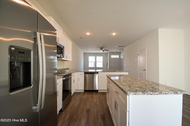 kitchen featuring sink, appliances with stainless steel finishes, white cabinets, a kitchen island, and kitchen peninsula