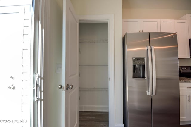 kitchen featuring stainless steel refrigerator with ice dispenser, white cabinetry, dark hardwood / wood-style floors, and light stone countertops