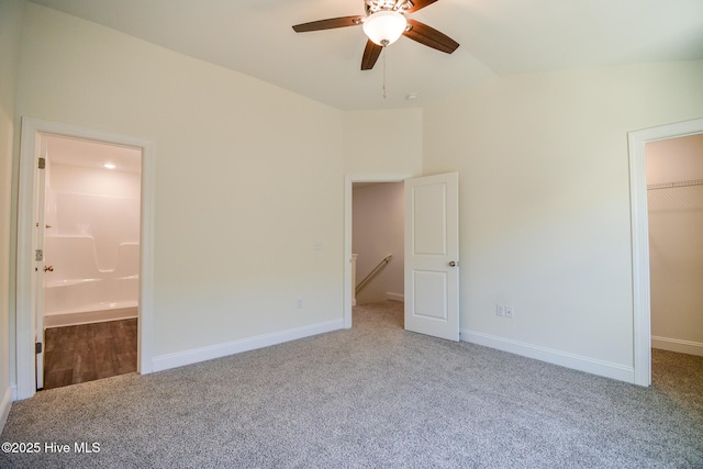 unfurnished bedroom with connected bathroom, light carpet, a spacious closet, vaulted ceiling, and a closet