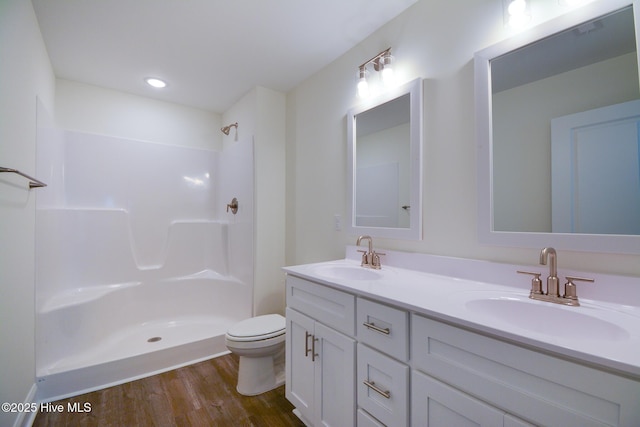 bathroom featuring vanity, hardwood / wood-style floors, a shower, and toilet