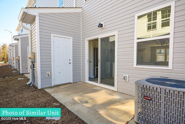 view of exterior entry with cooling unit and a patio area