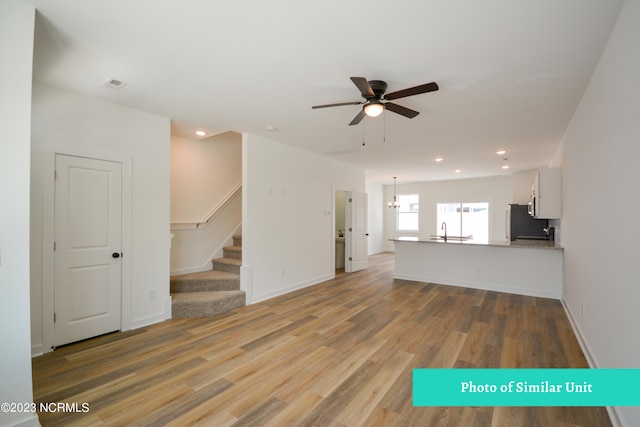 unfurnished living room featuring hardwood / wood-style floors, ceiling fan, and sink