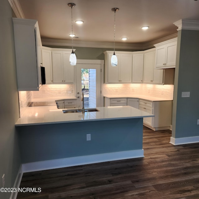 kitchen with sink, white cabinetry, ornamental molding, kitchen peninsula, and pendant lighting