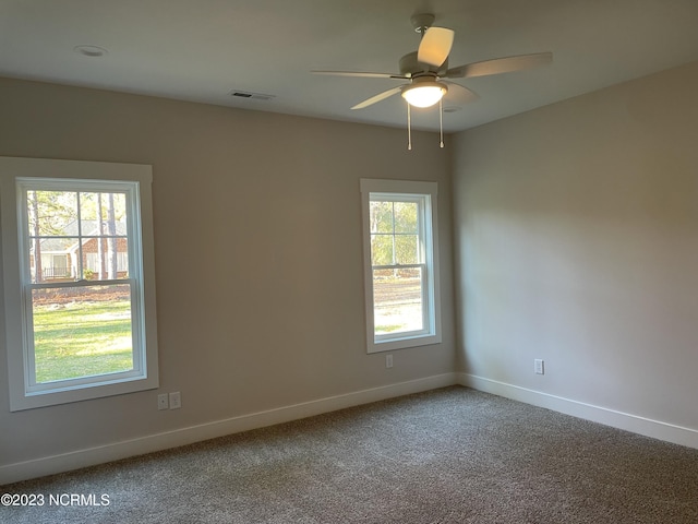 carpeted spare room with baseboards, visible vents, and ceiling fan