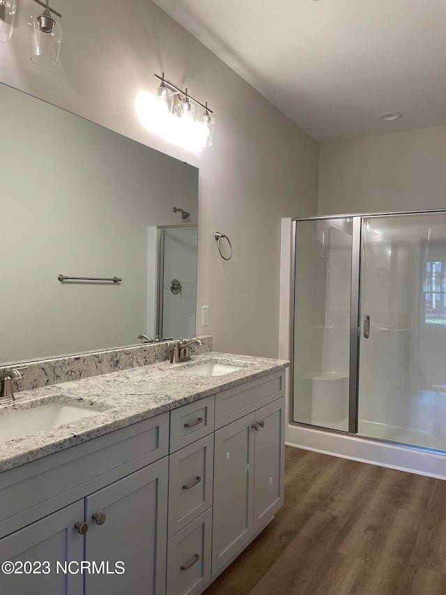 bathroom featuring dual vanity, hardwood / wood-style flooring, and a shower with door