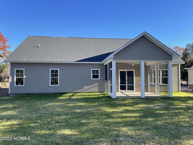 rear view of property with a sunroom, a yard, roof with shingles, and a ceiling fan