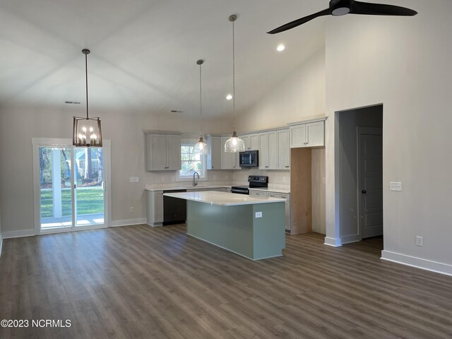 kitchen featuring dark hardwood / wood-style floors, ceiling fan with notable chandelier, a kitchen island, hanging light fixtures, and electric stove