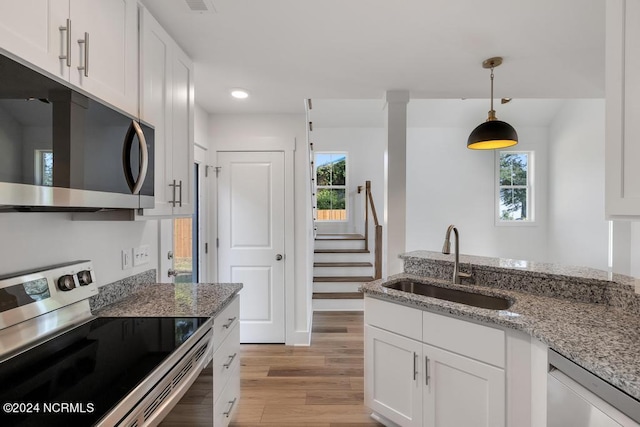 kitchen with light hardwood / wood-style floors, stainless steel appliances, sink, light stone counters, and white cabinets