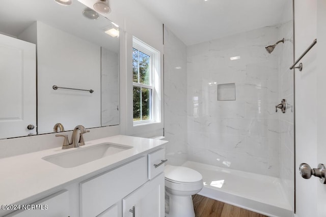 bathroom featuring tiled shower, toilet, hardwood / wood-style flooring, and vanity