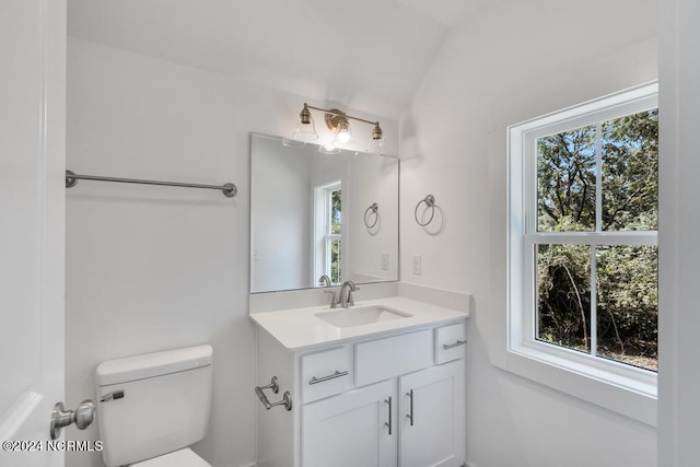 bathroom with lofted ceiling, vanity, toilet, and a healthy amount of sunlight