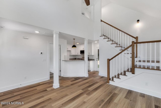 interior space featuring a high ceiling, hardwood / wood-style floors, and decorative columns