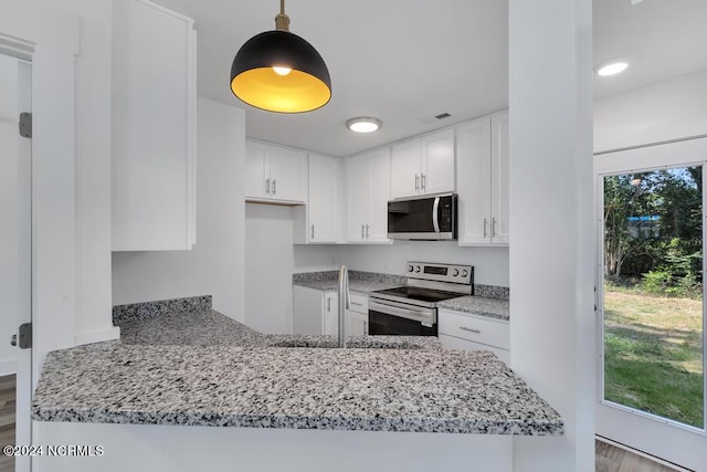 kitchen with a healthy amount of sunlight, kitchen peninsula, appliances with stainless steel finishes, and white cabinets