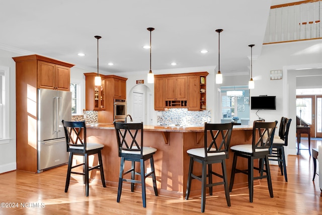 kitchen with a kitchen breakfast bar, appliances with stainless steel finishes, light hardwood / wood-style flooring, and light stone countertops