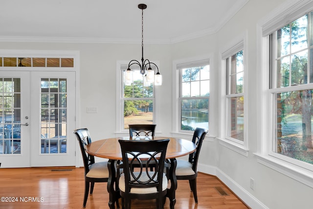 dining space featuring ornamental molding, light hardwood / wood-style floors, plenty of natural light, and a notable chandelier