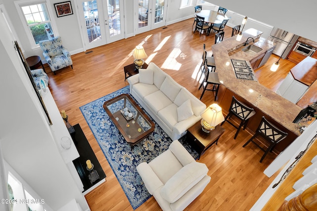 living room with light hardwood / wood-style flooring, sink, and french doors