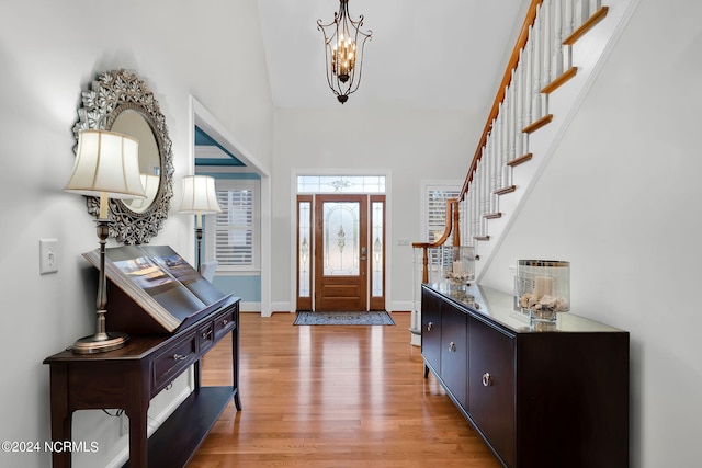 entryway with light hardwood / wood-style floors, a chandelier, and a high ceiling