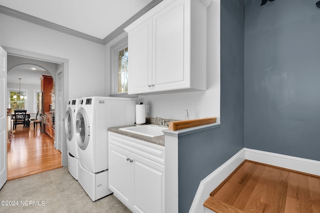 laundry room featuring washer and dryer, light hardwood / wood-style floors, a healthy amount of sunlight, and crown molding