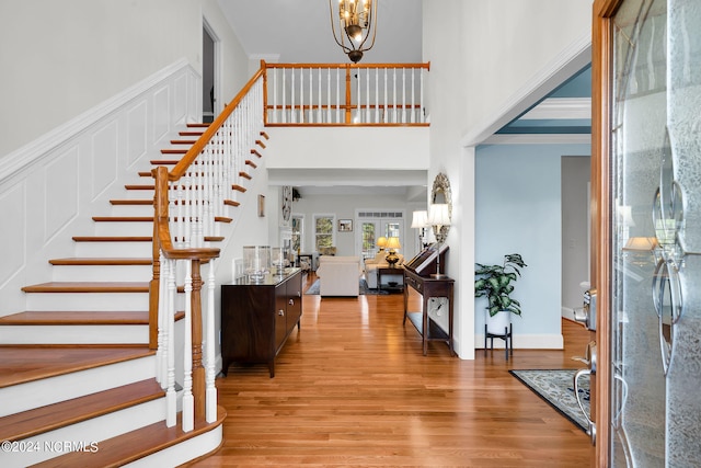 foyer entrance featuring an inviting chandelier, light hardwood / wood-style flooring, and a towering ceiling